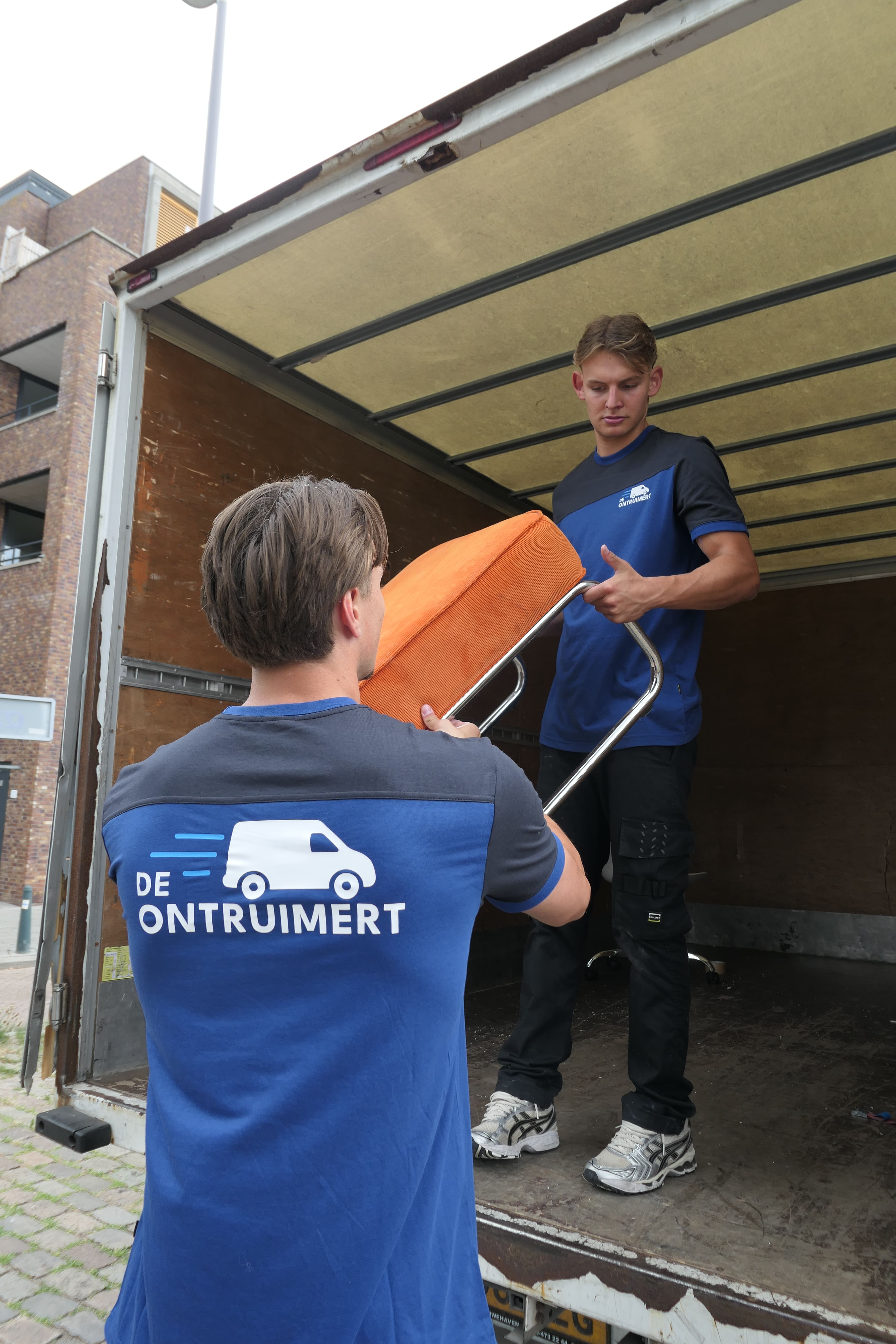 Twee ontruimers dragen een bankje